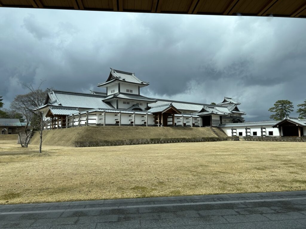 A view of the historic Kanazawa Castle under a dramatic, cloudy sky.