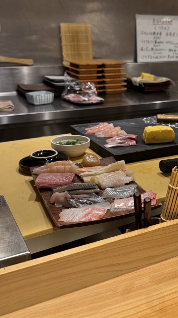 The chef's counter at Sushi Rekireki Omicho, showing a platter of fresh fish prepared for an omakase meal.
