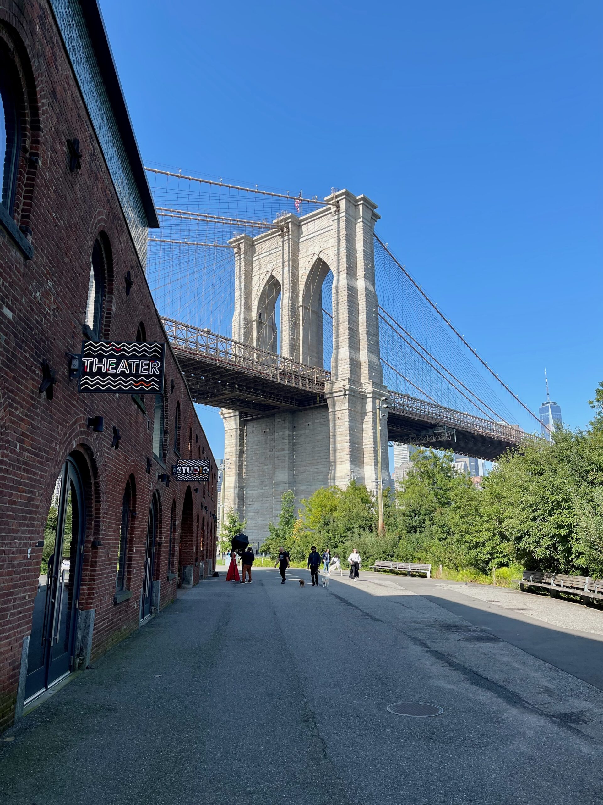 Brooklyn Bridge viewed from DUMBO with brick warehouses and One World Trade Center in the distance.