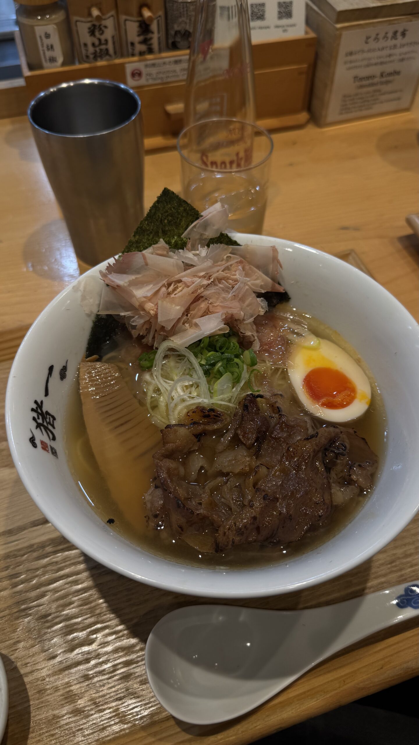 A bowl of ramen with chashu, egg and spring onion on a wooden counter in Kyoto.