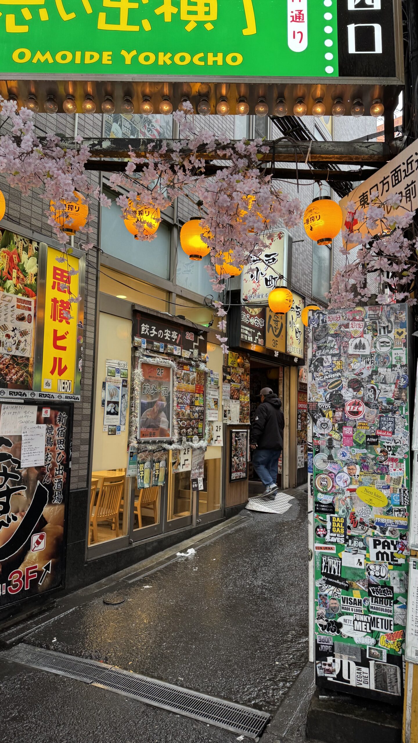 The entrance to Omoide Yokocho in Shinjuku, hung with signage and artificial blossom.