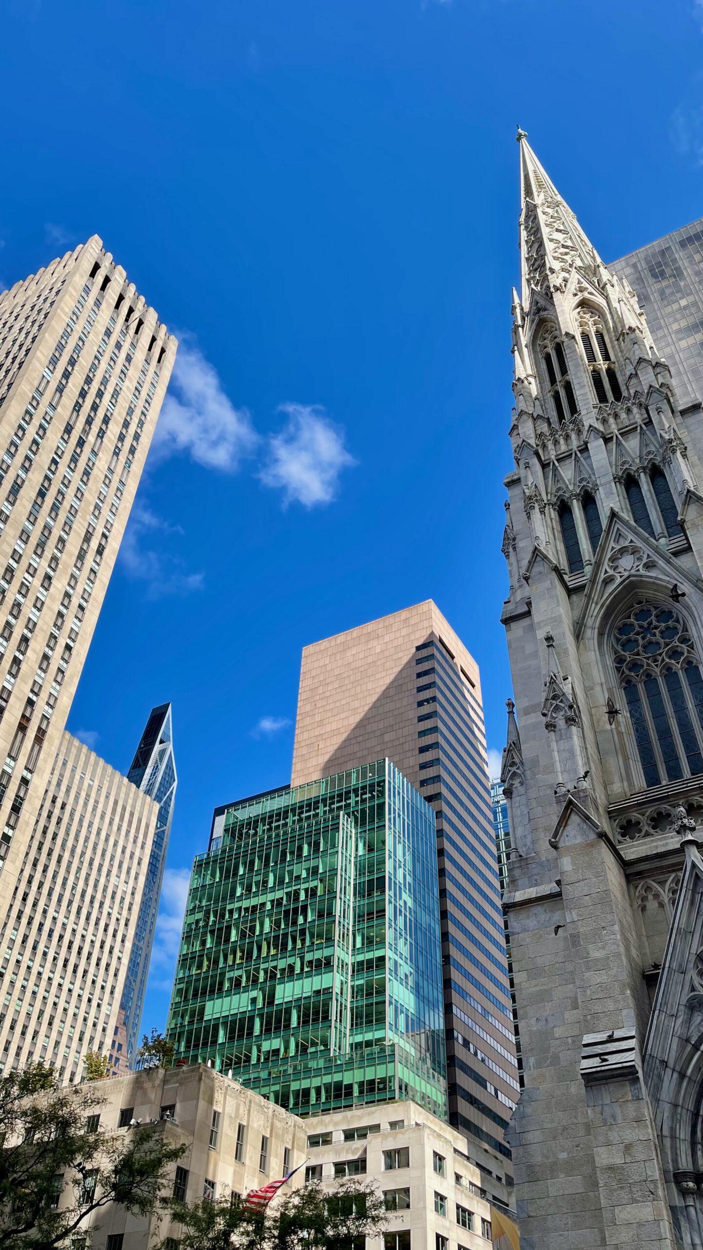 St. Patrick's Cathedral and Midtown skyscrapers under a blue sky.