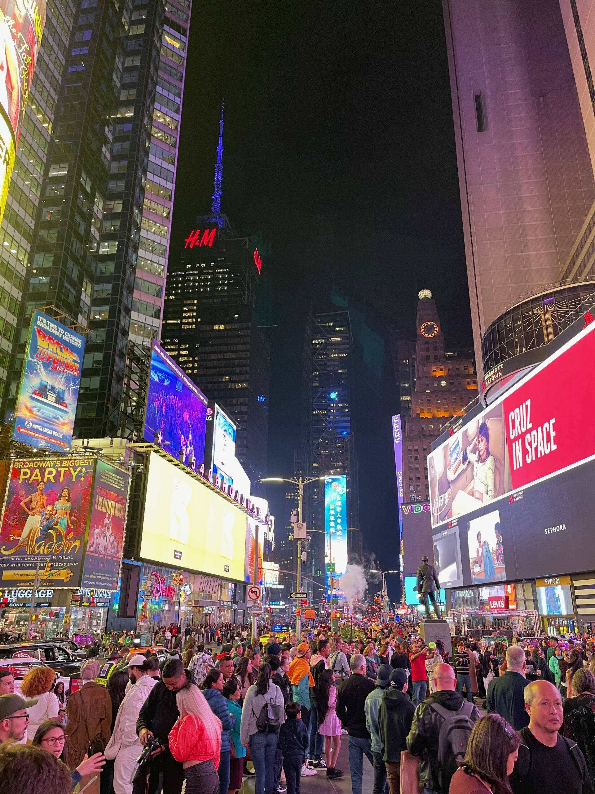 Crowds and illuminated billboards in Times Square at night.